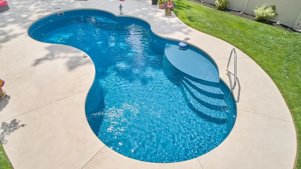 Freeform fiberglass pool with tanning ledge built by Imperial Pools & Hardscapes