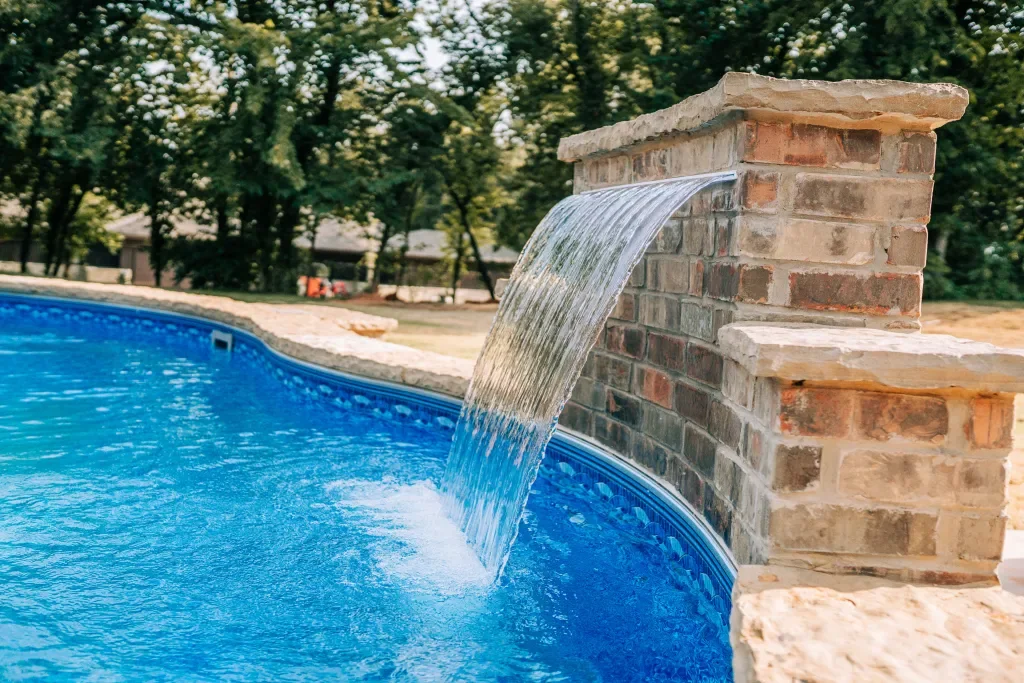 Brick sheer descent waterfall pouring into a pool built by Imperial Pools & Hardscapes